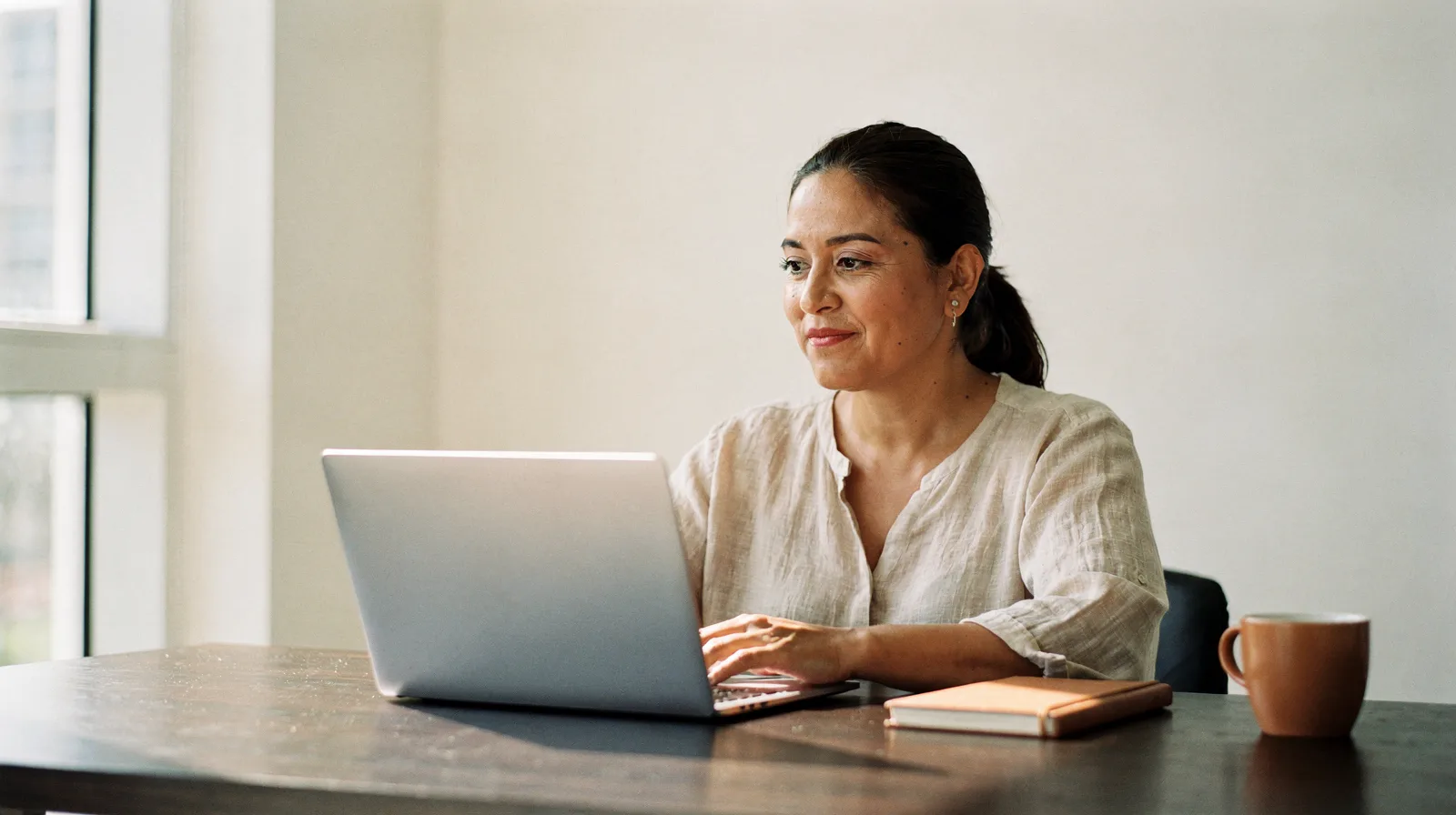 A small business owner working on a laptop at a bright office desk
